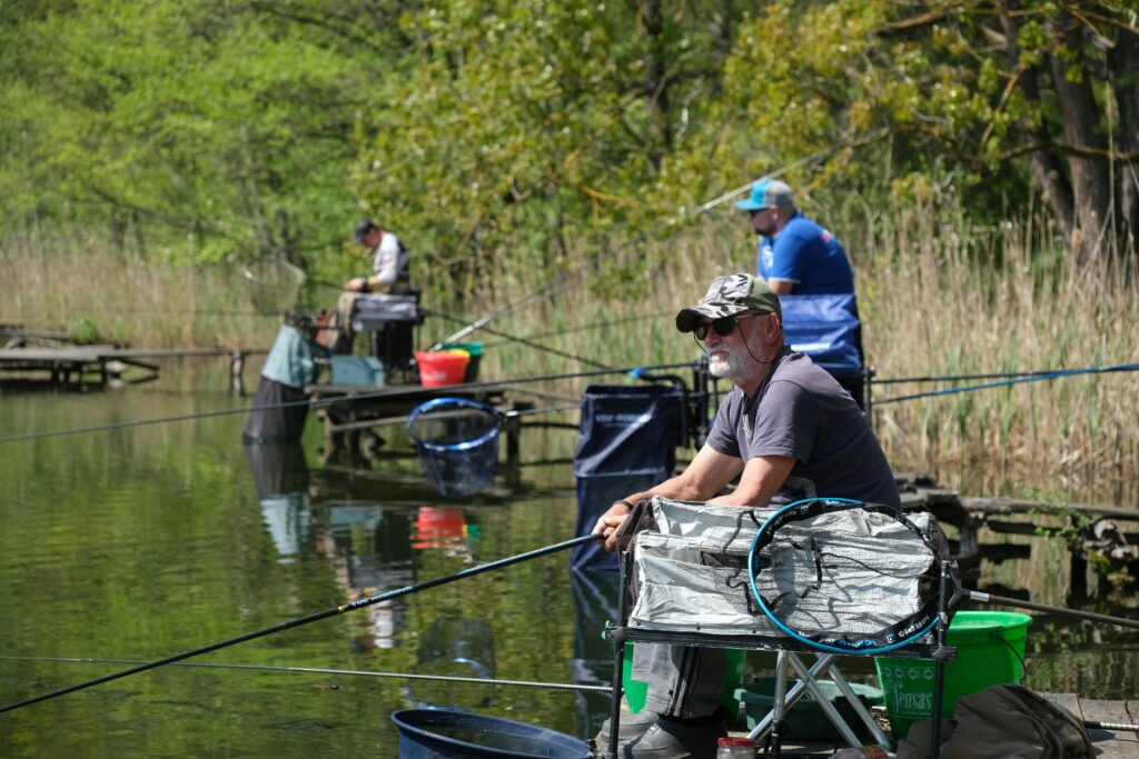 Three men enjoying a peaceful day fishing at a serene lakeside.